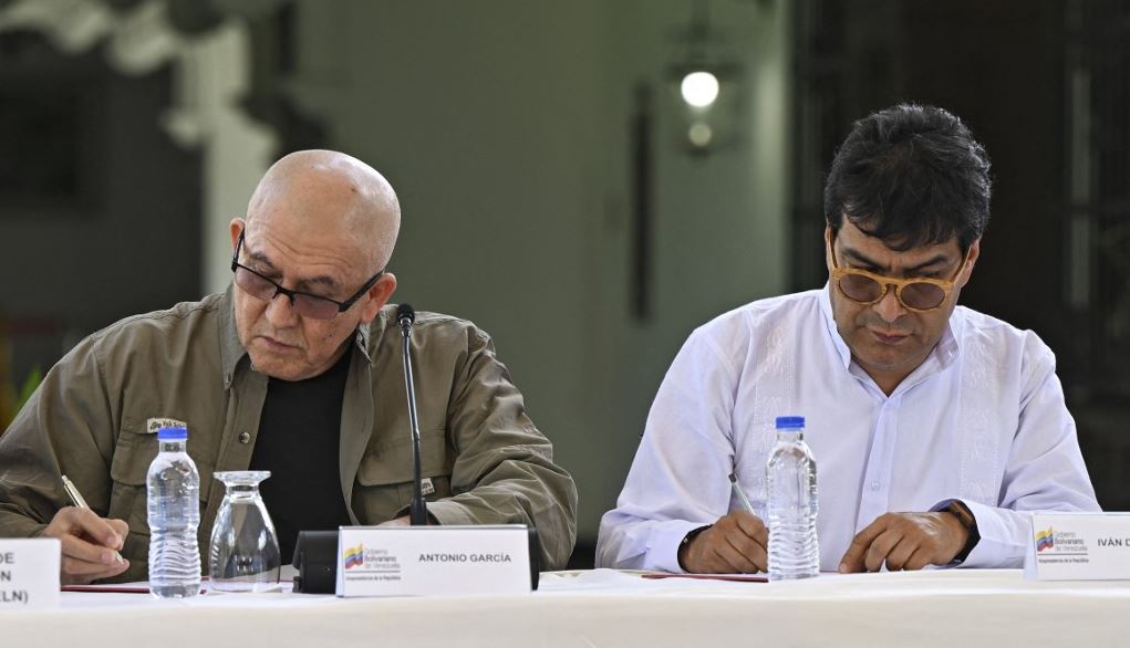 The first commander of the Colombian National Liberation Army (ELN), Antonio Garcia (L), and the Colombian government's Commissioner for Peace, Danilo Rueda, sign documents after announcing new peace talks, in Caracas, on October 4, 2022. /AFP
