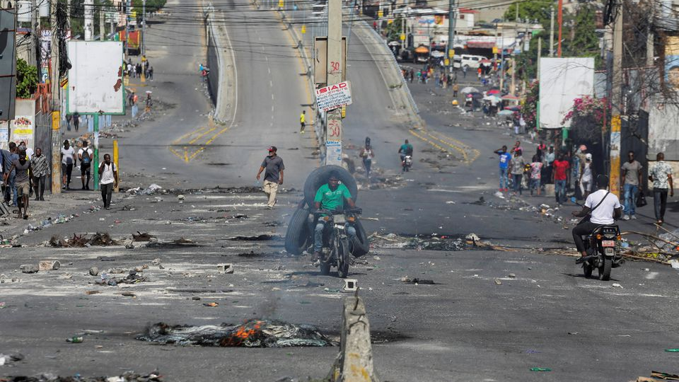 People pass through an empty street with remains of barricades during a nationwide strike against rising fuel prices, in Port-au-Prince, Haiti September 26, 2022. /REUTERS