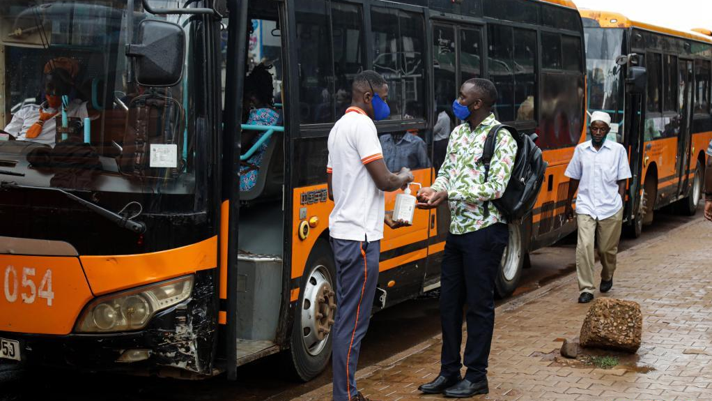 A bus operator sanitizes the hands of a passenger in Kampala, Uganda, August 2, 2021. /Xinhua
