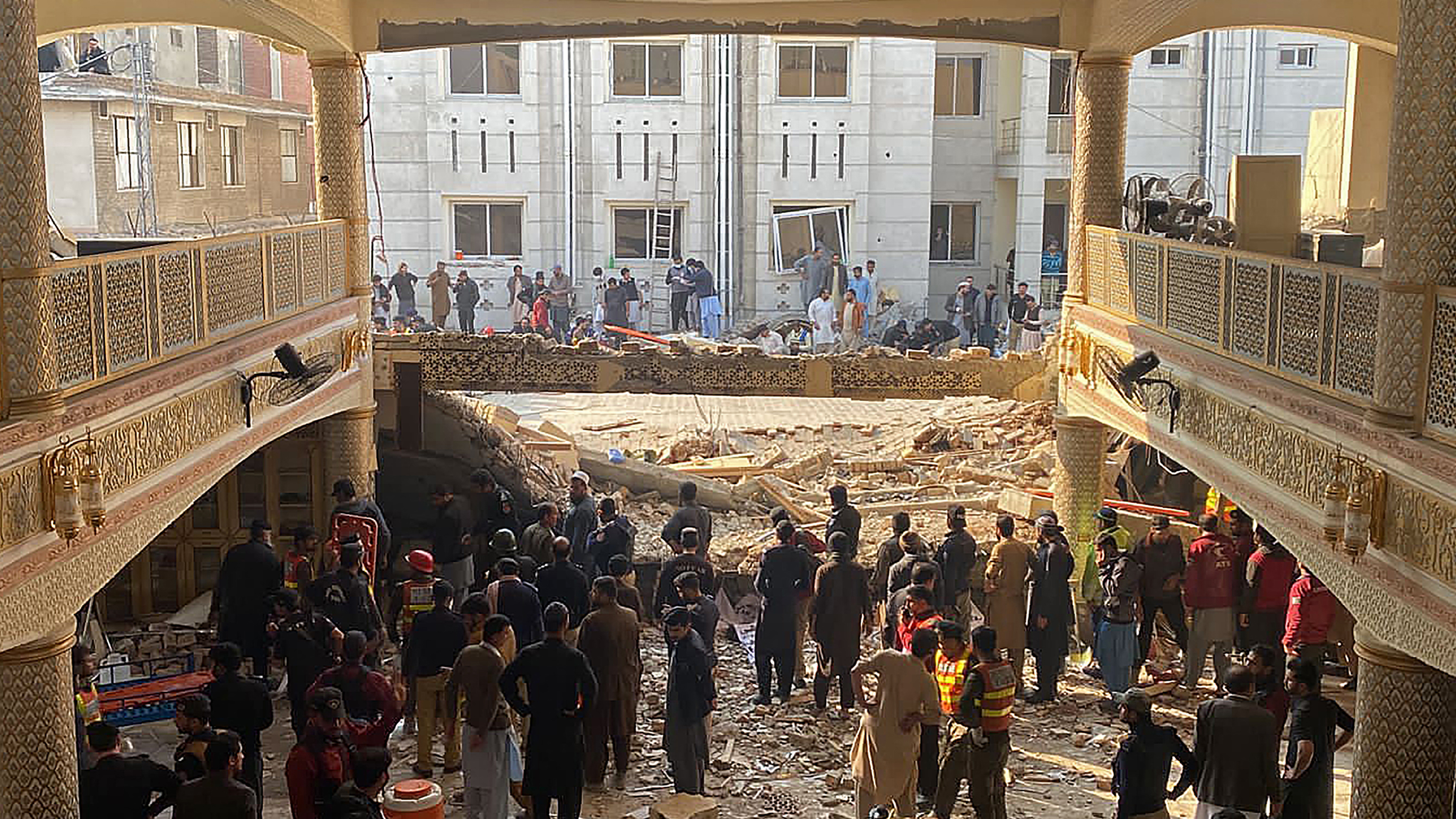 Plain-clothed policemen gather over the rubble of a damaged mosque following January's 30 suicide blast inside the police headquarters in Peshawar. /AFP
