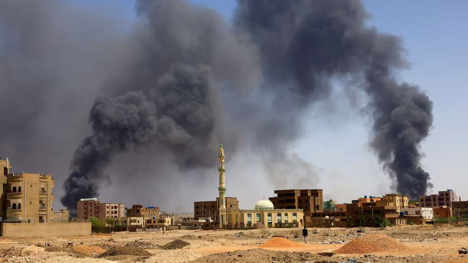 A man walks while smoke rises above buildings after aerial bombardment, during clashes between the paramilitary Rapid Support Forces and the army in Khartoum North, Sudan, May 1, 2023. /REUTERS