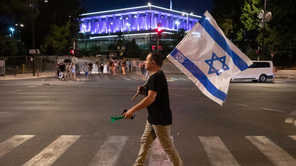 A protester against the Israeli government's judicial overhaul walks by the Israeli parliament, or Knesset, in Jerusalem, during a march from Tel Aviv to Jerusalem on July 22, 2023. /Xinhua