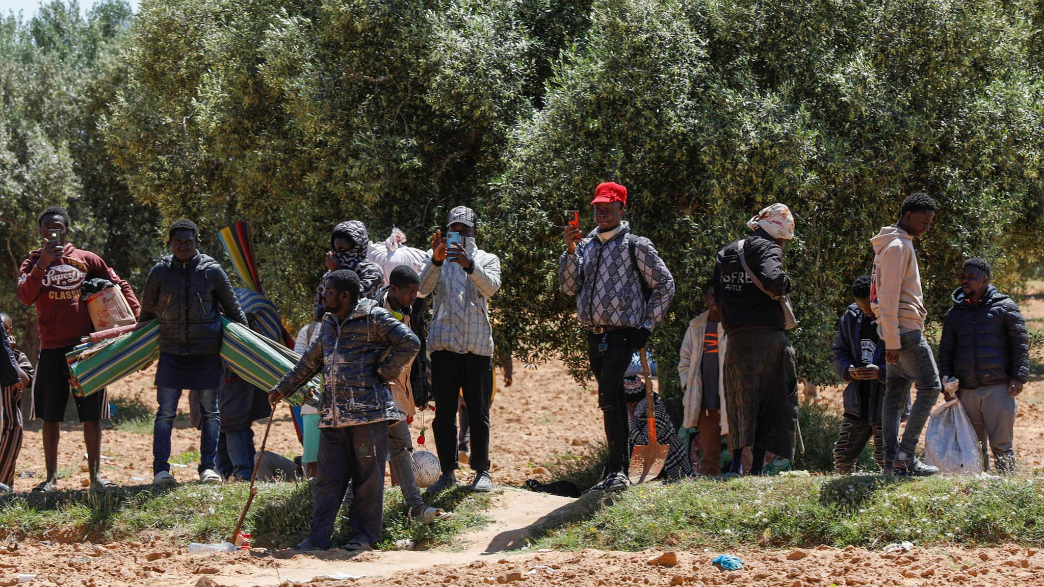 People leave with their belongings from a makeshift camp for migrants from sub-Saharan Africa as authorities dismantle the camp at al-Amra on the outskirts of the Tunisian city of Sfax on April 24, 2025. /CFP