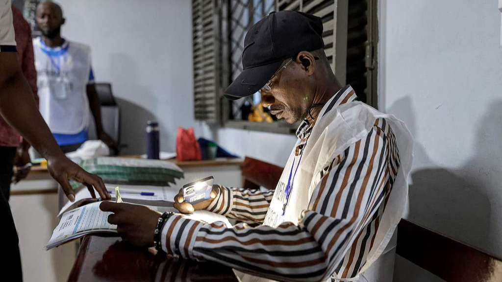 A General Directorate of Elections official checks a voter's information at a polling station in Conakry on December 28, 2025, before polls open during Guinea's presidential election. /CFP