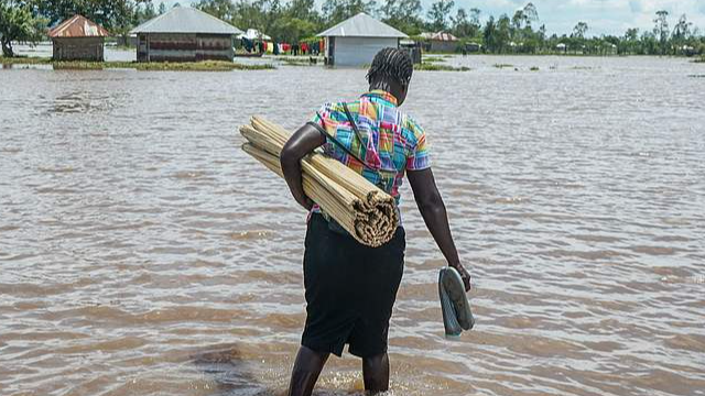 A resident carries her belongings as she walks through a flooded area in West Nyakach, Kisumu County, on March 22, 2026. /CFP