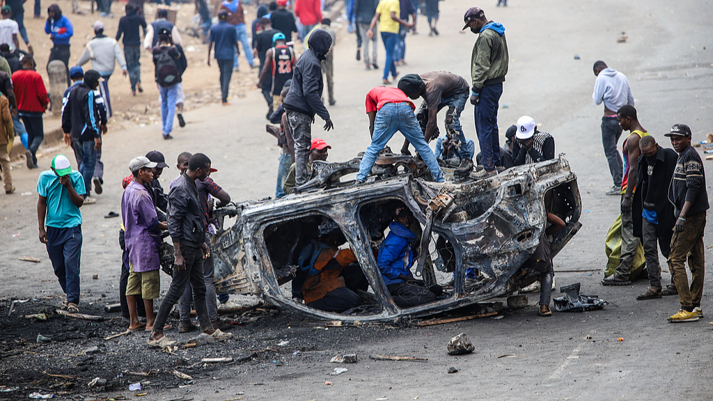 People strip parts from a burned-out vehicle during a public transport strike over fuel prices in Nairobi, Kenya, May 18, 2026. /CFP