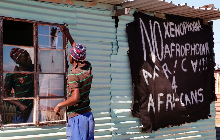 A man replaces a broken window at a tavern in Philippi township, next to a banner that reads: 