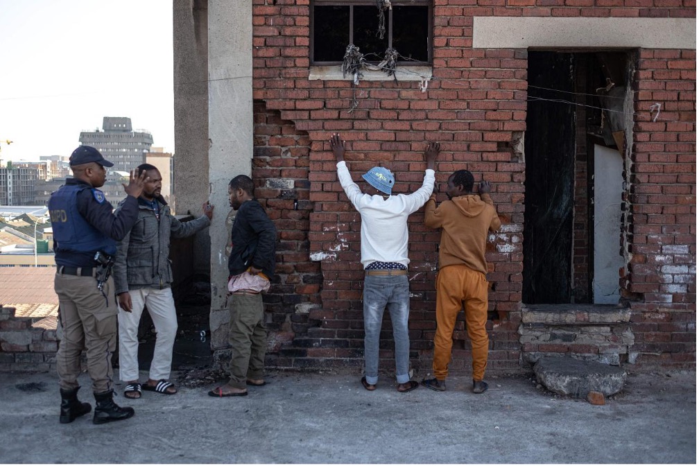A Johannesburg Metro Police Department officer questions suspected undocumented migrants on the rooftop of a highjacked building before arresting them in the Johannesburg CBD, July 1, 2025. /CFP