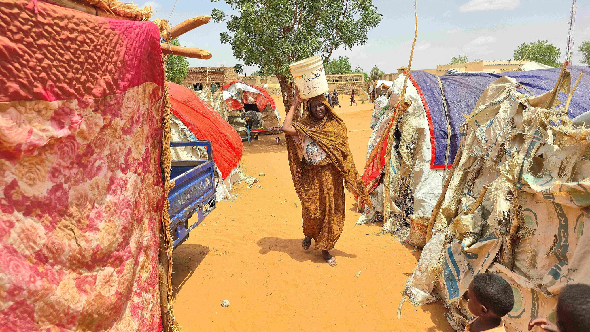 FILE: A Sudanese woman walks as she carries a plastic canister in al-Rahmaniyah camp for displaced people, near the city of El-Obeid in the southern Kordofan region, on June 25, 2026. /CFP