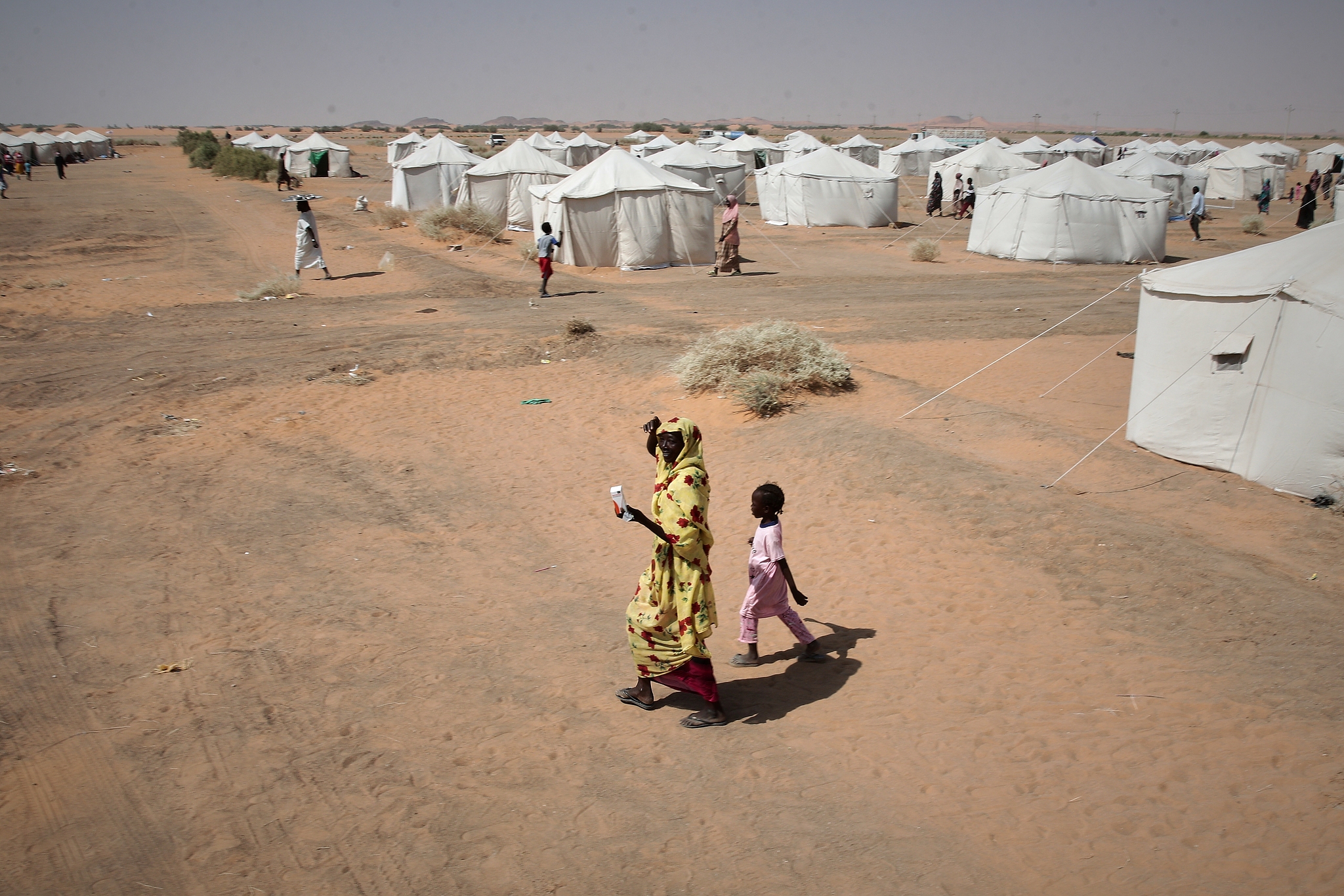 File photo: A woman and a child, displaced from North Darfur's capital, el-Fasher or other conflict-affected areas walk in the El-Afadh camp in Al Dabbah, in Sudan's Northern State, November 13, 2025. /CFP