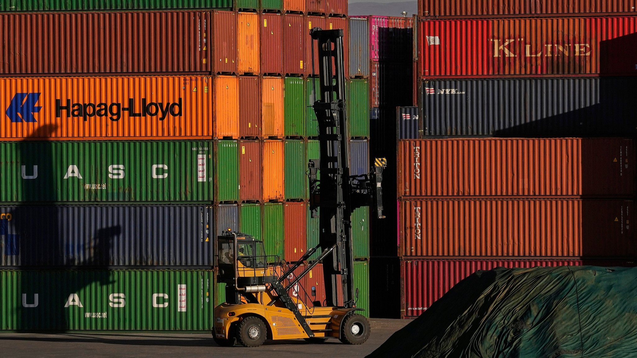 A heavy machine drives past stacked shipping containers in a warehouse in Johannesburg, South Africa on August 1, 2025. /CFP