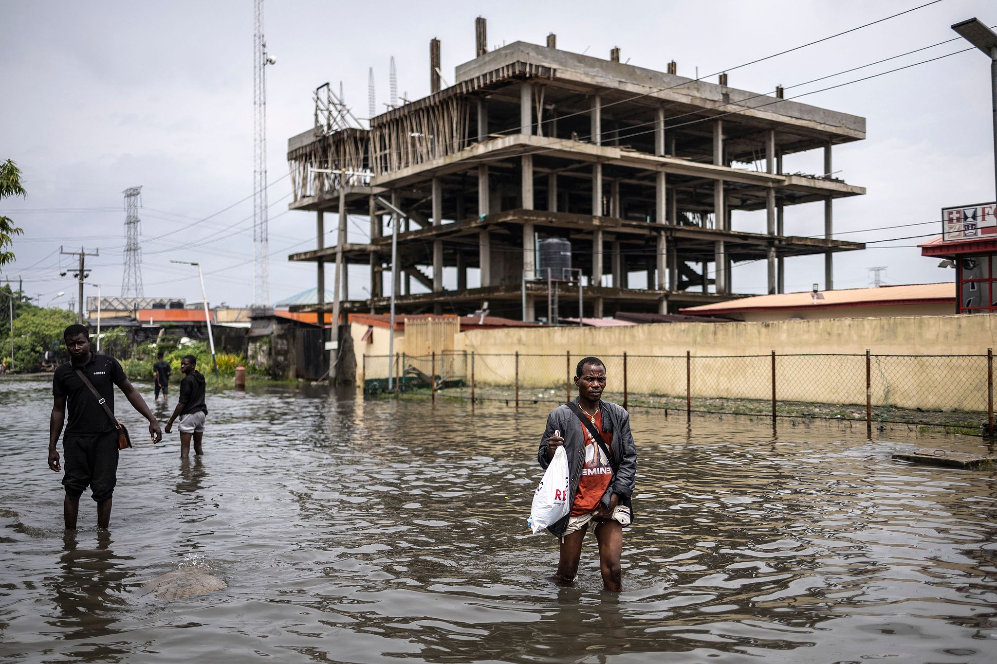 Pedestrians wade through a flooded street in Lekki neighborhood in Lagos, July 3, 2026. /CFP