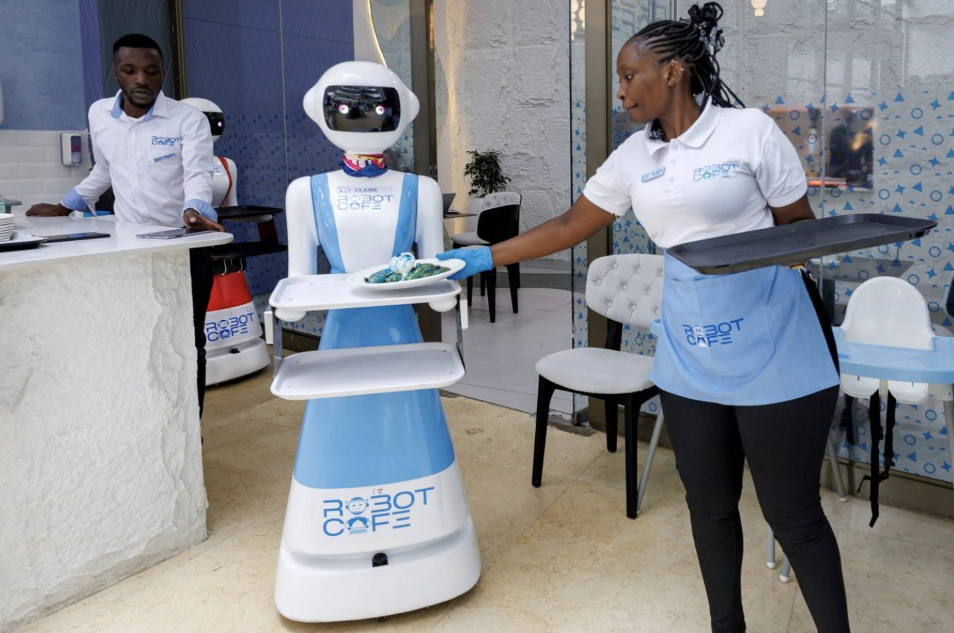 A robotic waiter receives a plate of waffles from a human colleague at the Robot Cafe, Kenya’s first restaurant to employ humanoid robots as waiters, in Nairobi, Kenya, August 27, 2024. /CFP