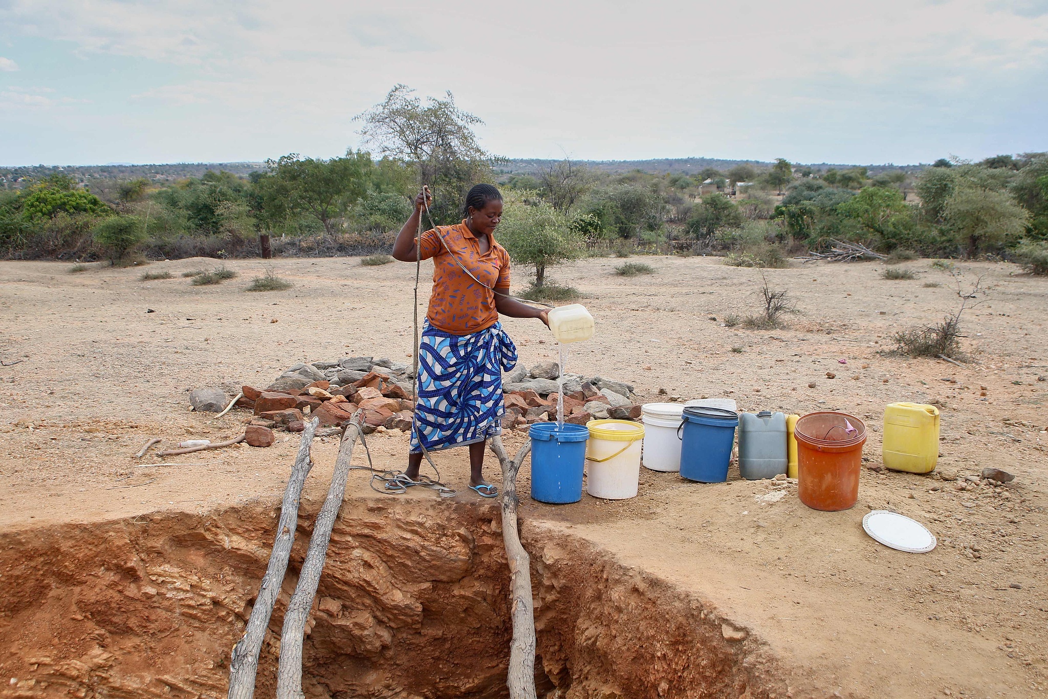 A woman pours a trickle of water from a village well into a bucket after the groundwater level has severely dried up due to drought caused by El Niño in Zimbabwe, July 2, 2024. /CFP