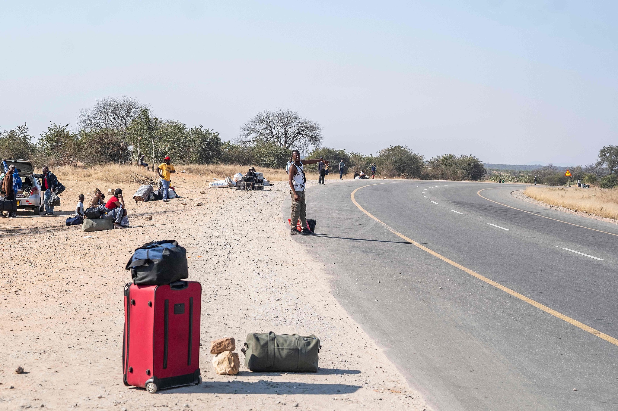 Zimbabwean migrants stand by the roadside with their luggage after returning home, July 10, 2026. /CFP