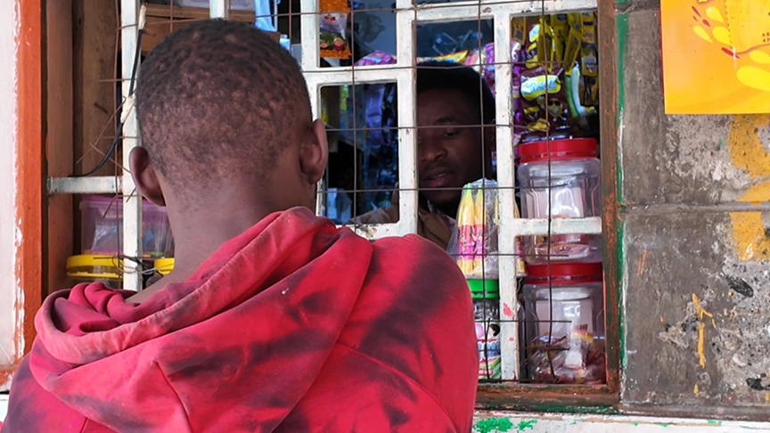 A customer makes a purchase at a local Nairobi kiosk as vendors prepare for heavy rains. /CGTN Africa