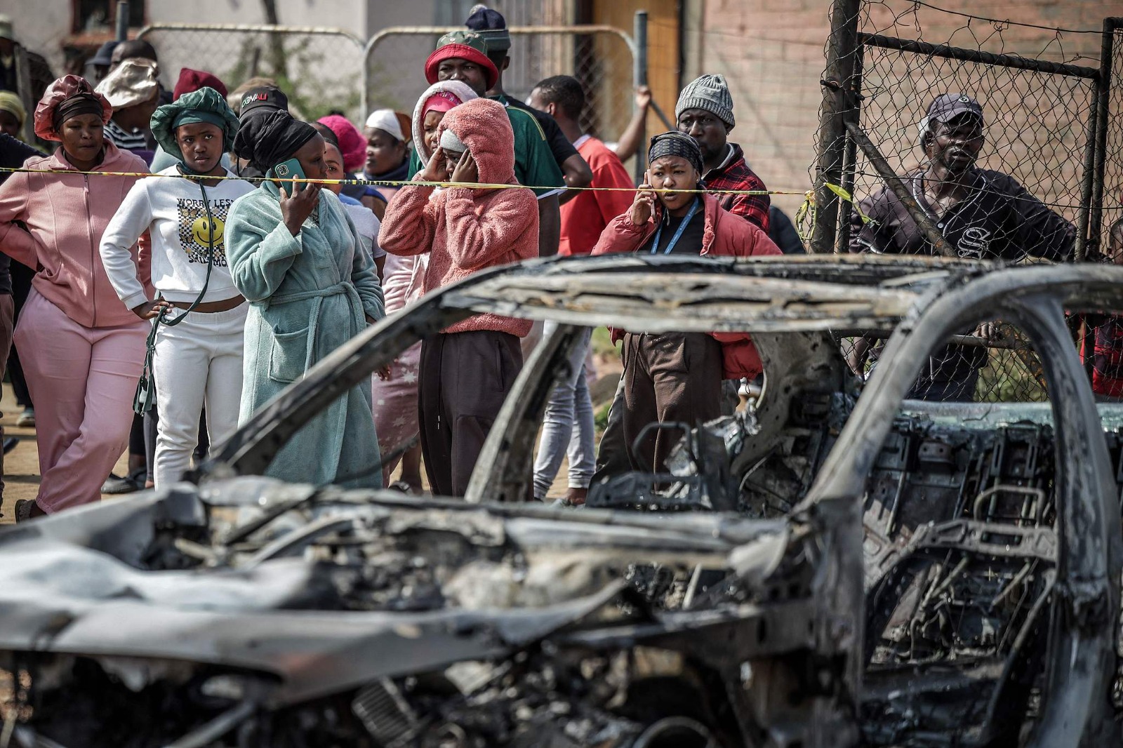 Residents stand behind police tape near the scene where gunmen armed with assault rifles stormed a bar in Carletonville, west of Johannesburg, South Africa, on September 27, 2026. /VGG