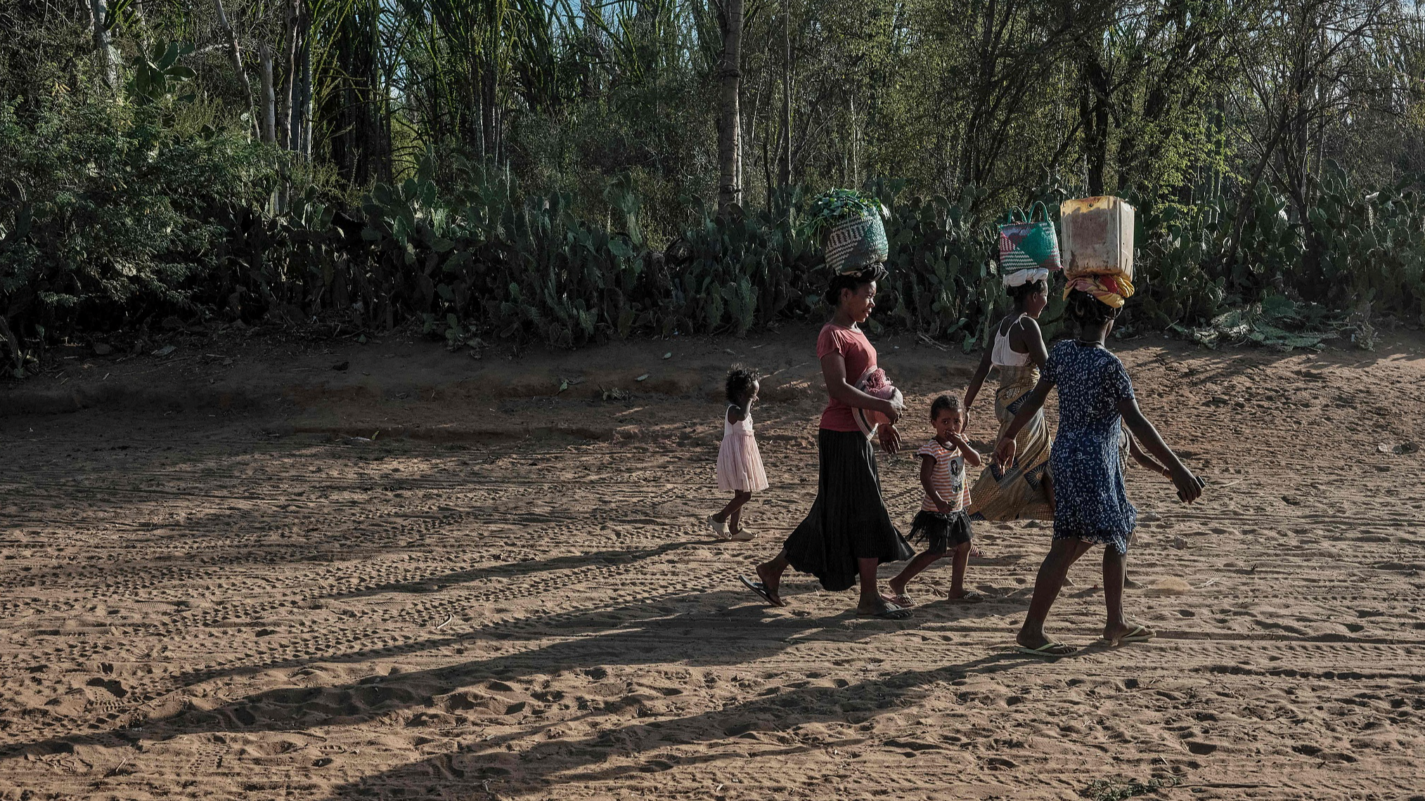 People walk from a market while balancing their purchased food and household supplies on their heads in Ifotaka, in southern Madagascar, September 23, 2026. /VCG