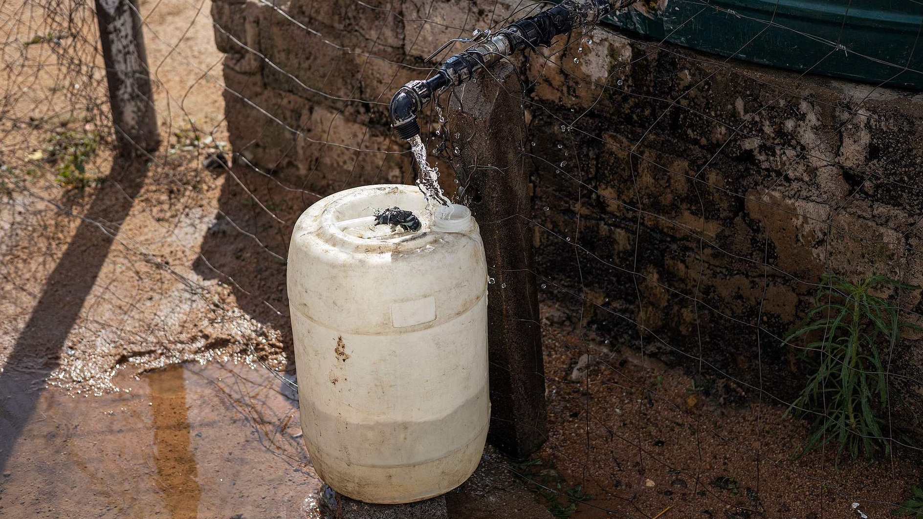 A general view of a jar being filled with water from a tank in an informal settlement in Hammanskraal on May 23, 2023. /VCG